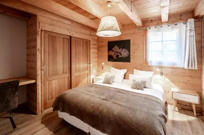 a bedroom with a large bed in a wooden room at Les Couadzous Samoëns Centre, Sauna, Jacuzzi, 6 chambres, 7 salles de bains, 16 pers 250 m2 in Samoëns