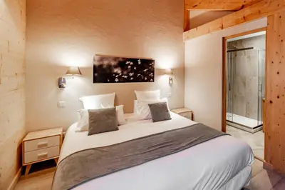 a bedroom with a large white bed and a window at Les Couadzous Samoëns Centre, Sauna, Jacuzzi, 6 chambres, 7 salles de bains, 16 pers 250 m2 in Samoëns