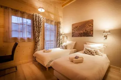 two twin beds in a room with a window at Les Couadzous Samoëns Centre, Sauna, Jacuzzi, 6 chambres, 7 salles de bains, 16 pers 250 m2 in Samoëns