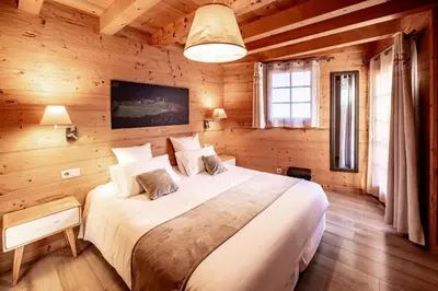 a bedroom with a large bed in a wooden room at Les Couadzous Samoëns Centre, Sauna, Jacuzzi, 6 chambres, 7 salles de bains, 16 pers 250 m2 in Samoëns