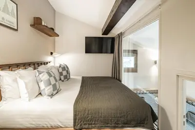 a bedroom with a bed and a television on the wall at Appartements de l'Héliopic in Chamonix-Mont-Blanc