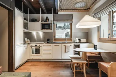 a kitchen with white cabinets and a table at Appartements de l'Héliopic in Chamonix-Mont-Blanc