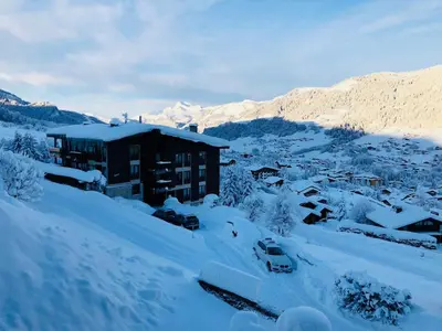 a building covered in snow with cars parked in it at Superbe duplex with Hammam-Spa in Megève in Megève