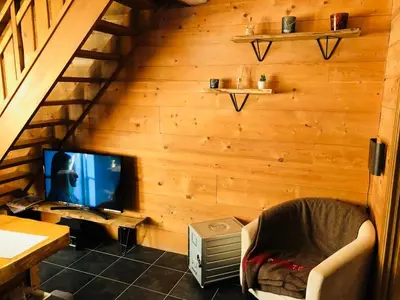 a room with a tv and a chair and a table at Superbe duplex with Hammam-Spa in Megève in Megève