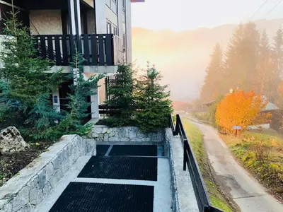 a house with a stone retaining wall next to a street at Superbe duplex with Hammam-Spa in Megève in Megève