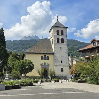 a large building with a clock tower in a courtyard at Le Miroir De Saint-Jacques in Sallanches