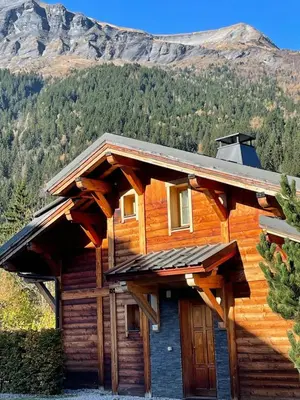 a log cabin with a mountain in the background at Chalet Nuances certifié 5 étoiles in Les Contamines-Montjoie