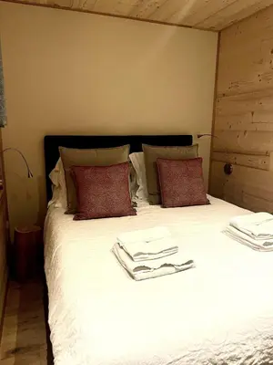 a bed with white sheets and red pillows at Chalet Nuances certifié 5 étoiles in Les Contamines-Montjoie