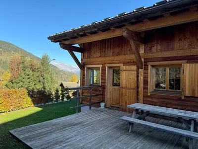 a wooden cabin with a bench on a deck at Chalet Nuances certifié 5 étoiles in Les Contamines-Montjoie