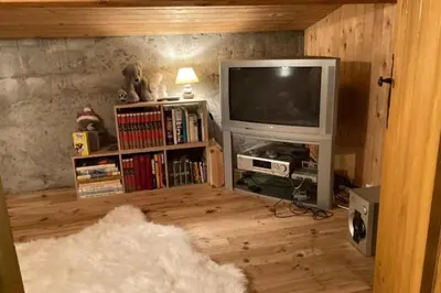 a living room with a television and a book shelf at Sumptuous chalet with breathtaking mountain views in Megève
