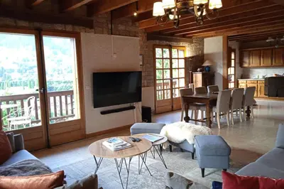 a living room with a television and a table with chairs at Sumptuous chalet with breathtaking mountain views in Megève