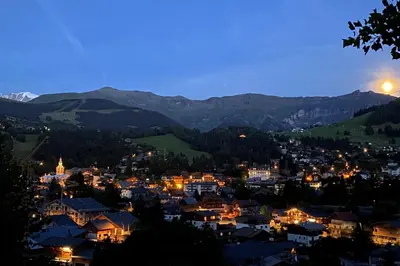 a view of a town at night with the moon at Sumptuous chalet with breathtaking mountain views in Megève
