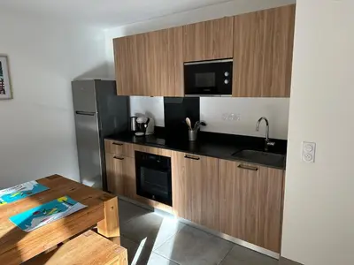 a kitchen with wooden cabinets and a sink and a refrigerator at Appartement neuf tout confort super emplacement in Samoëns