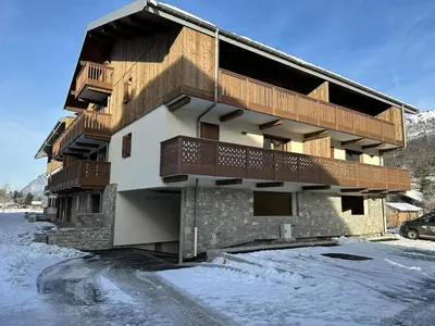 a building with wooden balconies on it in the snow at Appartement neuf tout confort super emplacement in Samoëns