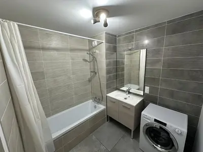 a bathroom with a washing machine and a washer at Appartement neuf tout confort super emplacement in Samoëns