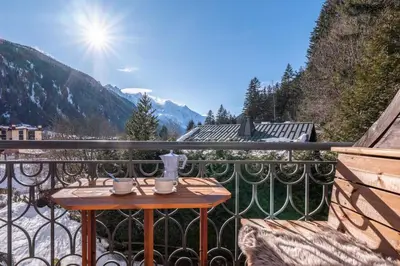 a table on a balcony with a view of the mountains at Le Cristal MT10 - Central Apartment - Close to ski lift - FreeParking in Chamonix-Mont-Blanc