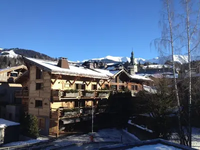 a building with snow on the roof and a church at LE CLOS DE RENNEs in Megève