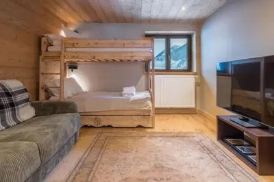 a living room with two bunk beds and a flat screen tv at Chalet Les Grands Montets in Chamonix-Mont-Blanc