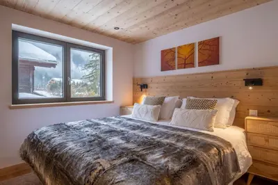 a bedroom with a large bed and two windows at Chalet Les Grands Montets in Chamonix-Mont-Blanc