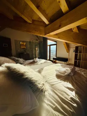 a bedroom with two beds with white sheets and a ceiling at Chalet Monarch - Les Carroz - Sauna, Spa & vue Montagnes in Arâches-la-Frasse