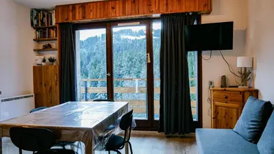 a living room with a table and a large window at Appartement Proche Des Pistes By TerraAlpina in Saint-Gervais-les-Bains
