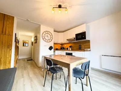 a kitchen with a table and chairs and a clock on the wall at Appartement Proche Des Pistes By TerraAlpina in Saint-Gervais-les-Bains