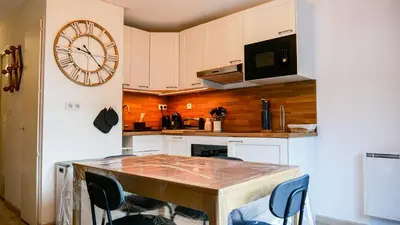a kitchen with a table and a clock on the wall at Appartement Proche Des Pistes By TerraAlpina in Saint-Gervais-les-Bains