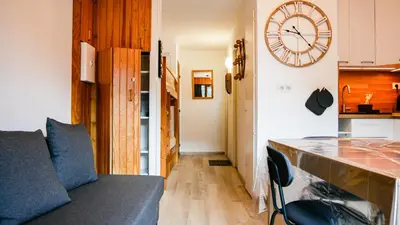a living room with a clock on the wall and a couch at Appartement Proche Des Pistes By TerraAlpina in Saint-Gervais-les-Bains