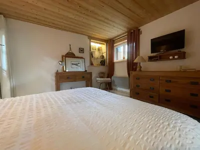 a bedroom with a white bed and a television at Chalet paisible avec cheminée et animaux acceptés près des pistes - FR-1-624-176 in Sixt