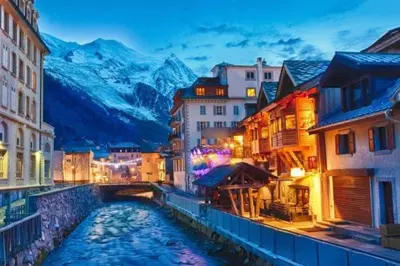 a river in a city with buildings and a mountain at Au Coin du Mont Blanc in Chamonix-Mont-Blanc