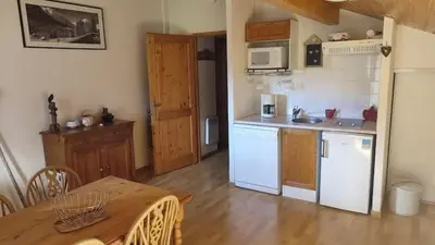 a kitchen with white appliances and a wooden table at Studio Résidence grand tetras in Samoëns