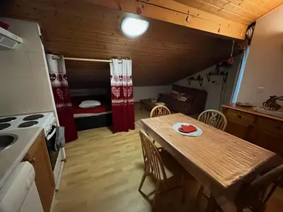 a kitchen with a table and a room with a bed at Studio Résidence grand tetras in Samoëns