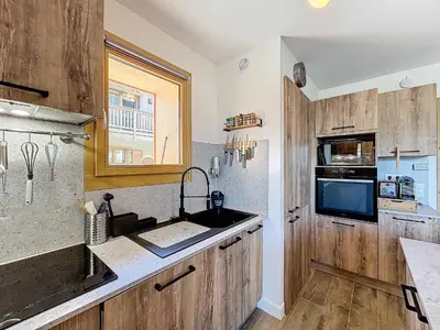 a kitchen with wooden cabinets and a sink and a window at Appartement standing à Combloux avec balcon et parking - FR-1-560-156 in Combloux