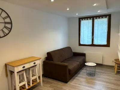 a living room with a brown couch and a clock at Le Flocon - Centre - Megève - Wifi - Duplex in Megève