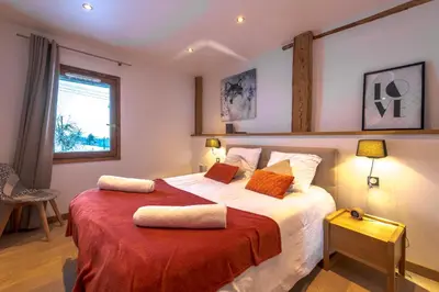 a bedroom with a large bed with a red blanket at Chalet Les Rots Home in Samoëns