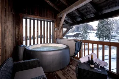 a hot tub on the deck of a cabin at Chalet Les Rots Home in Samoëns