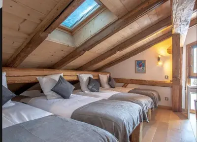 a row of four beds in a room with wooden ceilings at Chalet Les Rots Home in Samoëns