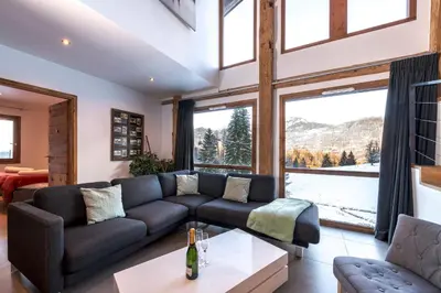 a living room with a couch and a large window at Chalet Les Rots Home in Samoëns