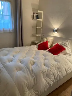 a white bed with two red pillows on it at Parfait pour 6 personnes au pied des télécabines in Saint-Gervais-les-Bains