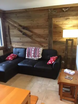 a black leather couch in a living room with a table at Appartement de charme familial aux CARROZ d ARACHES in Arâches-la-Frasse