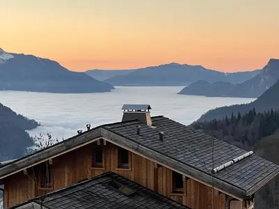 a living room with a black couch and a wooden wall at Appartement de charme familial aux CARROZ d ARACHES in Arâches-la-Frasse