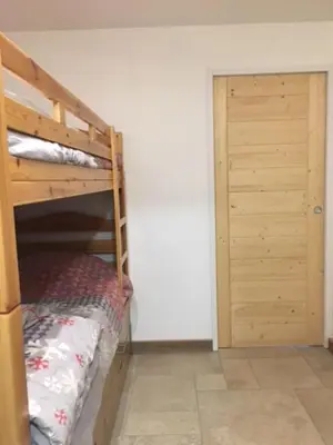 a bed in a room with a wooden wall at Appartement de charme familial aux CARROZ d ARACHES in Arâches-la-Frasse