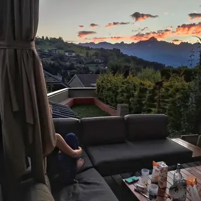 a person sitting on a couch watching the sunset at La Cabane Charmant T2 avec jardin centre village in Saint-Gervais-les-Bains