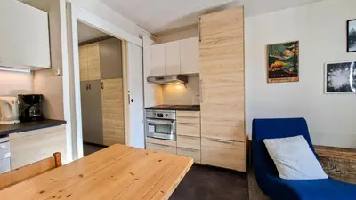 a kitchen with a wooden table and a blue chair at Résidence Verseau - Appartement lumineux et spacieux · Centre station · avec cabine et Balcon MAE-7781 in Magland