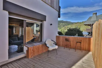 a patio with a couch and chairs on a wooden deck at Stunning luxury apartment in Megève