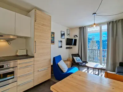 a kitchen and living room with a table and blue chairs at Appartement spacieux 6 pers, balcon, Flaine centre - FR-1-425-229 in Arâches-la-Frasse