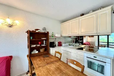 a kitchen with white cabinets and a wooden floor at 2-room apartment with balcony close to the slopes in Combloux