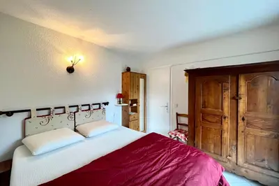 a bedroom with a large bed and a wooden door at 2-room apartment with balcony close to the slopes in Combloux