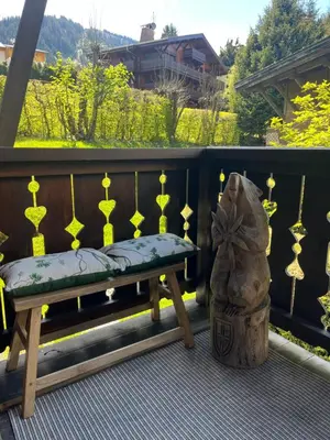 a wooden bench sitting on a porch with a chair at Confort et Proximité in Megève