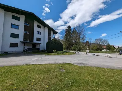 a white building with a grass yard next to a street at Appartement T3 avec 3 balcons et parking, proche centre - FR-1-624-26 in Samoëns